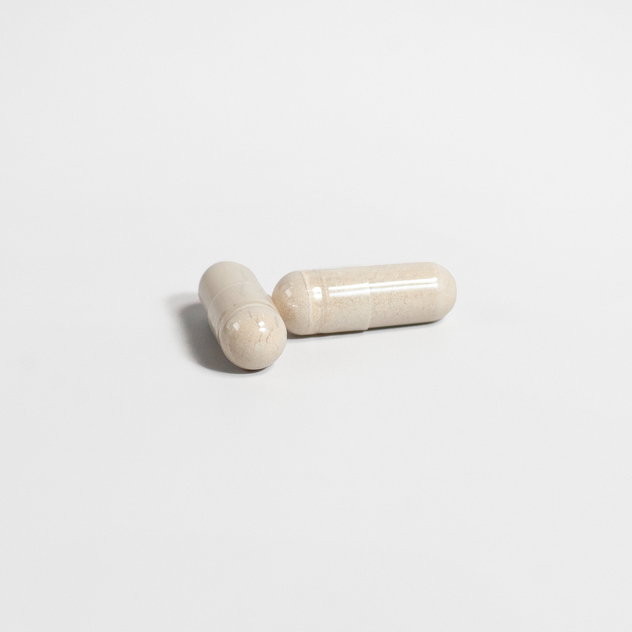 Two beige ceramic items resembling capsules on a light gray background