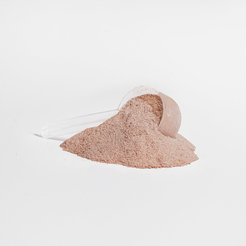 Small white bucket filled with pinkish-brown sand on a light gray background