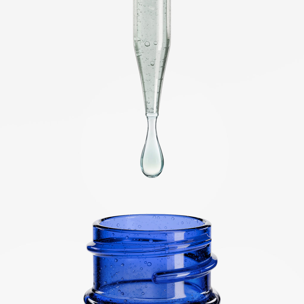 Glass dropper with clear liquid over a blue container on a white background