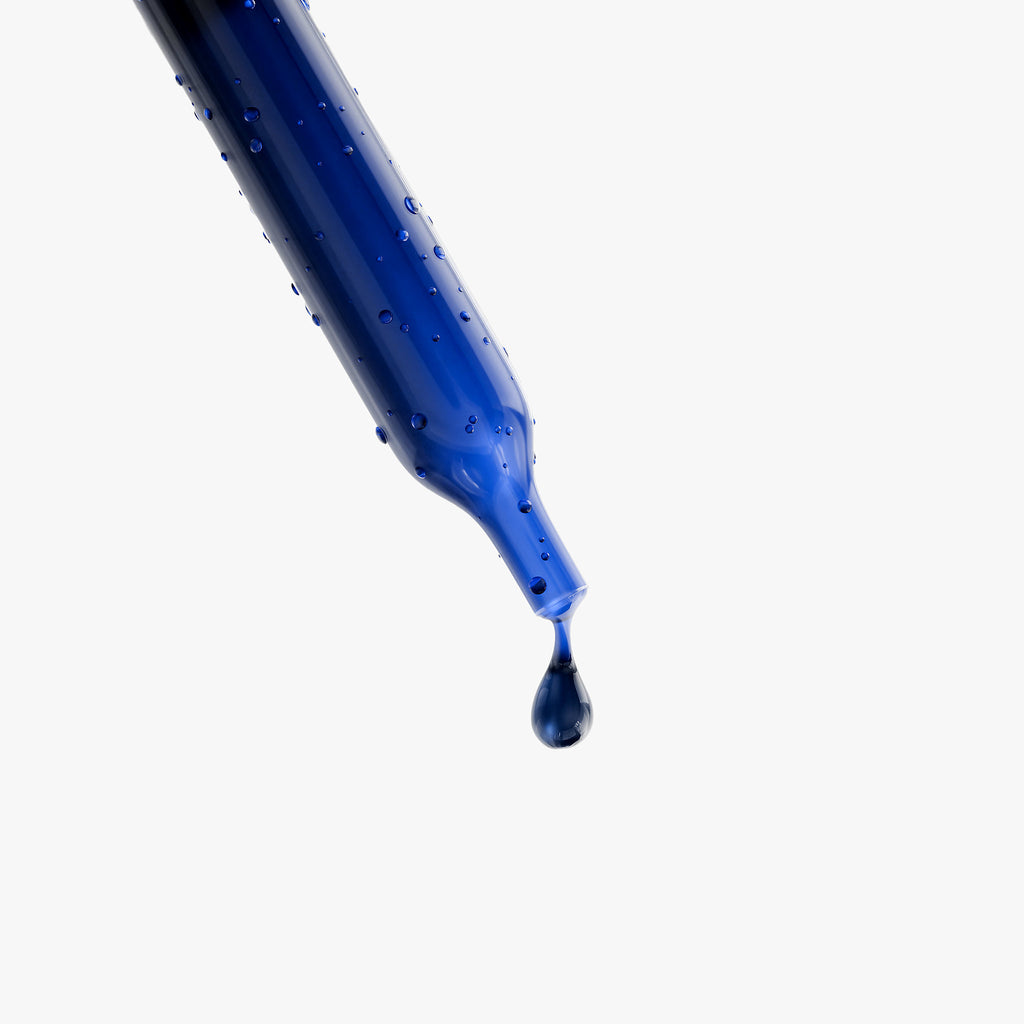 Blue liquid being dripped from a pipette on a white background
