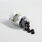 Bottle of black pills with a label on a light gray background