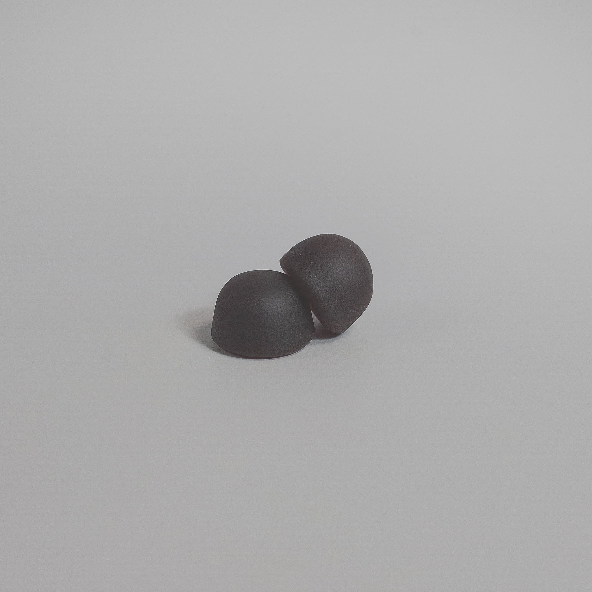 Two gray earbuds on a light gray background