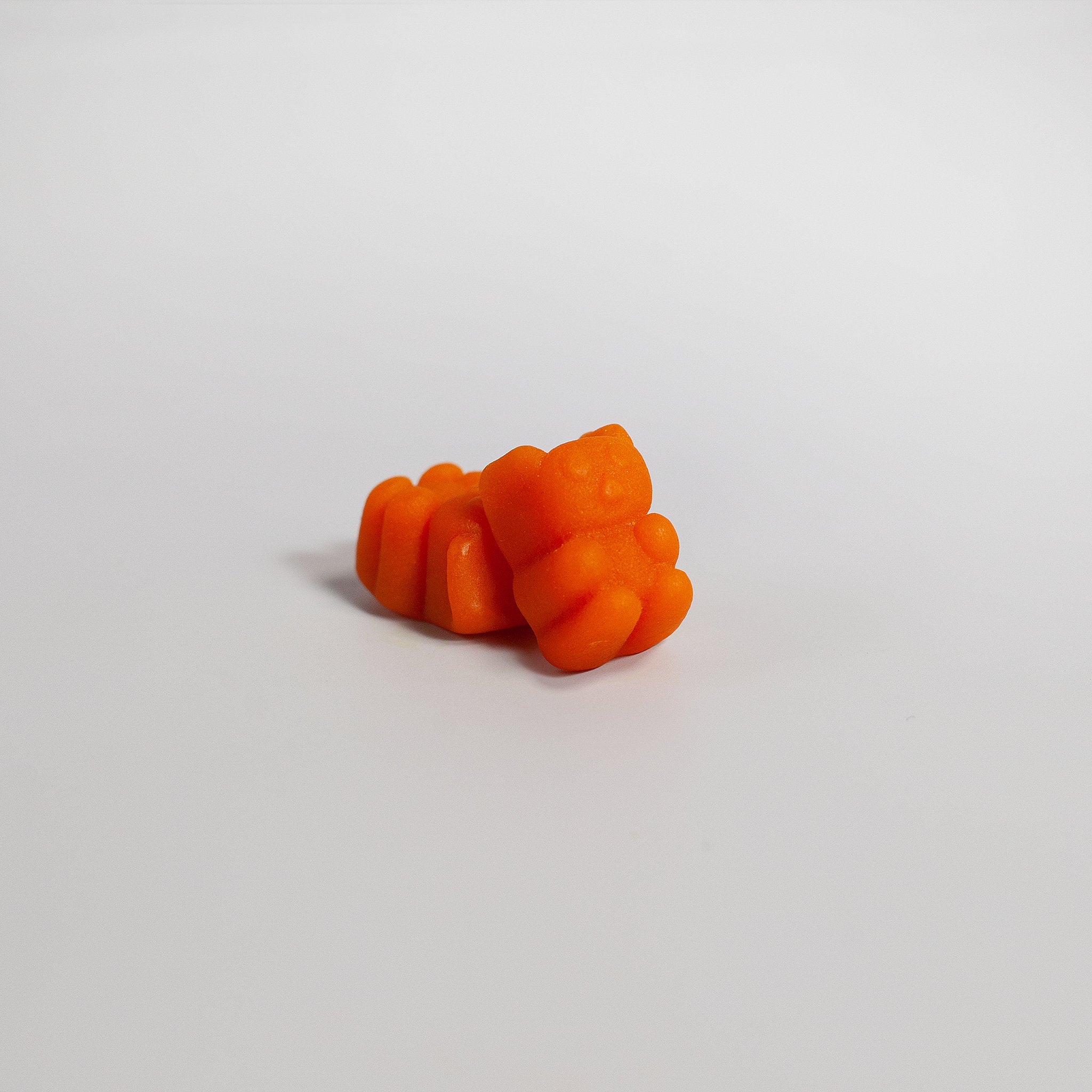 Orange gummy candy on a light gray background